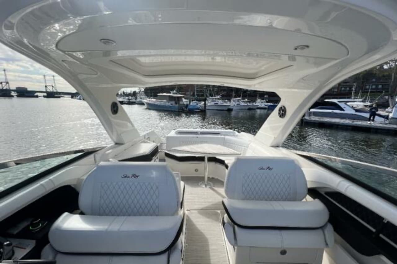 The cockpit of Après Sea: twin white captain's seats under a hardtop with a skylight, wraparound seating aft.